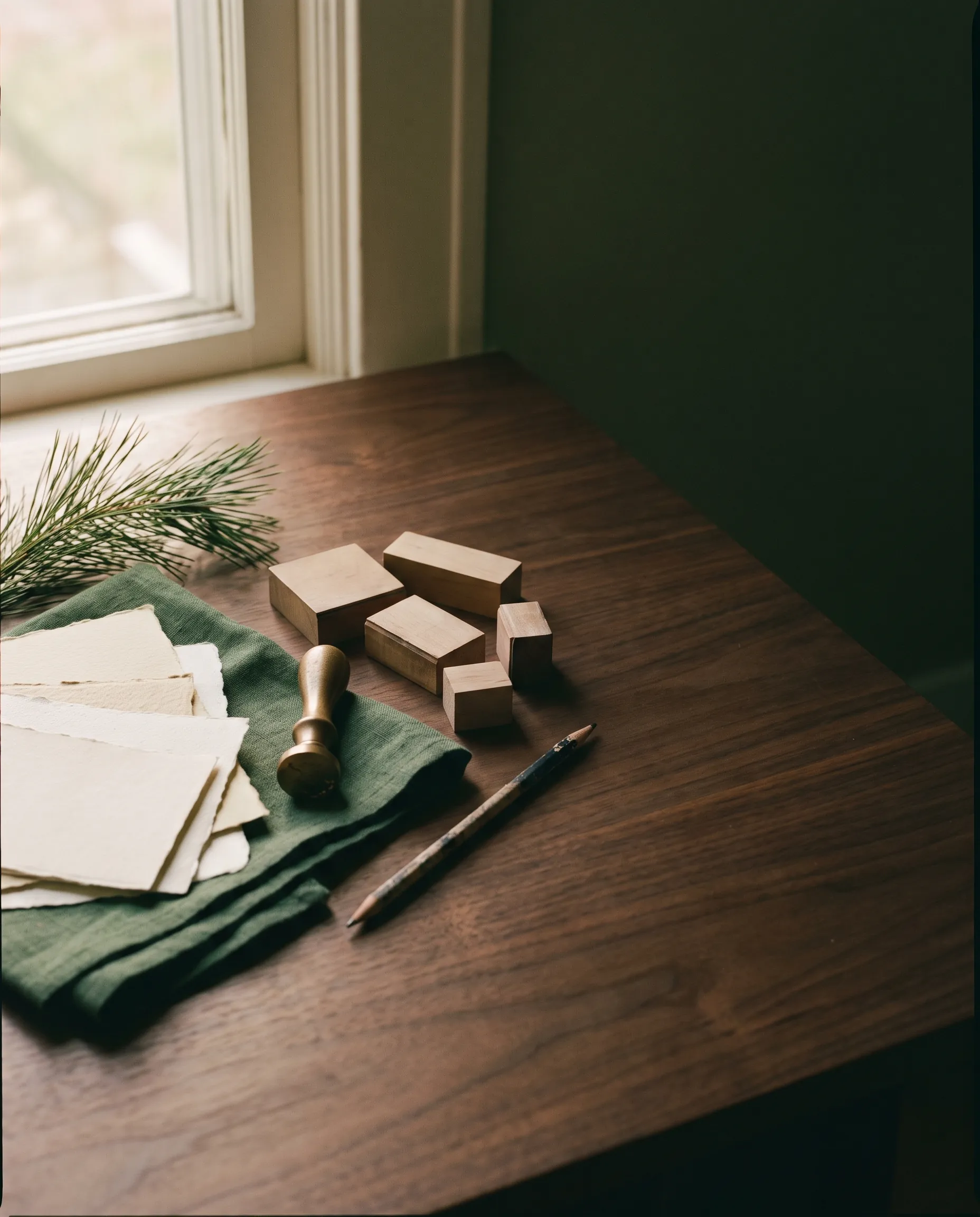 Paper swatches, green linen and a brass seal on a walnut table